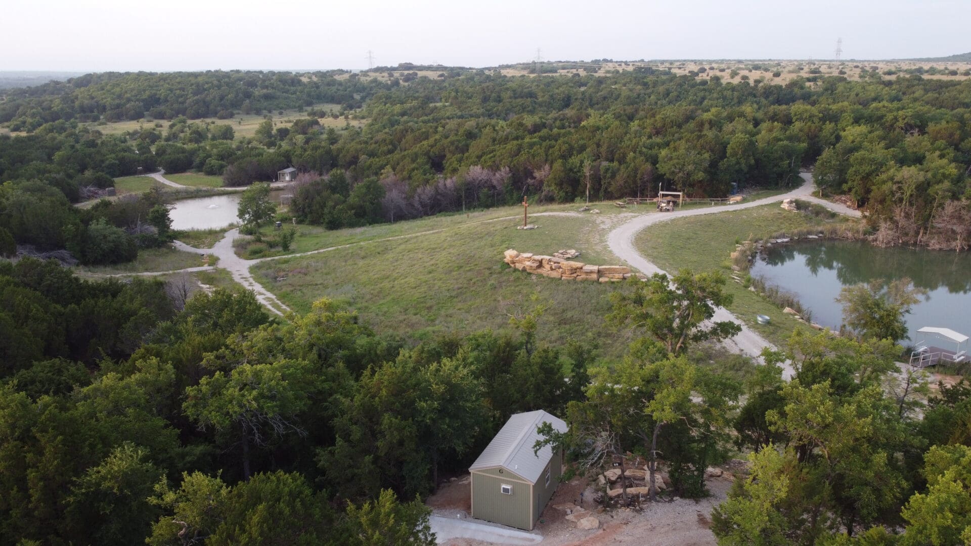 A large field with many trees and some buildings