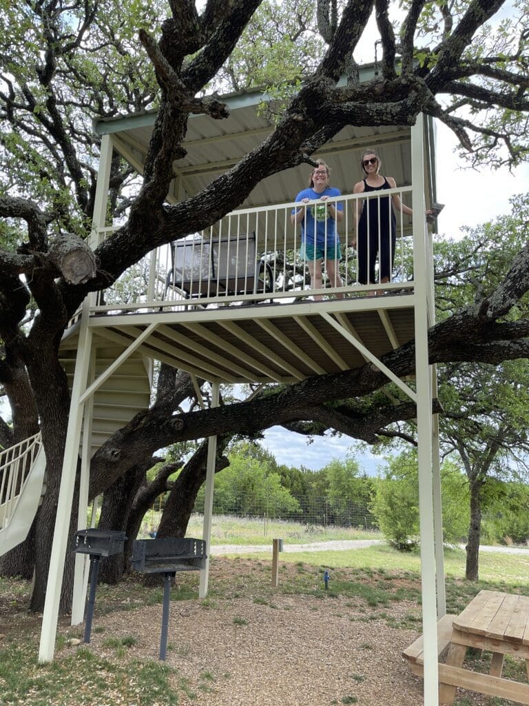 Two people standing on top of a tree house.