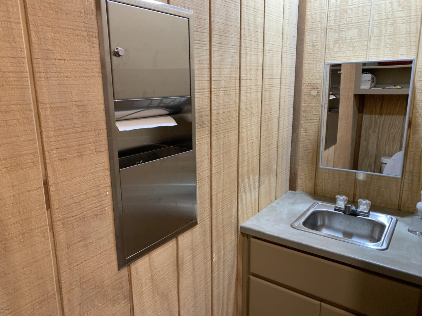 A bathroom with wood paneling and stainless steel fixtures.