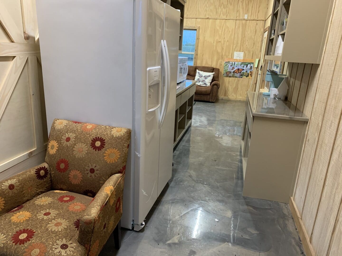 A kitchen with a refrigerator and chairs in it