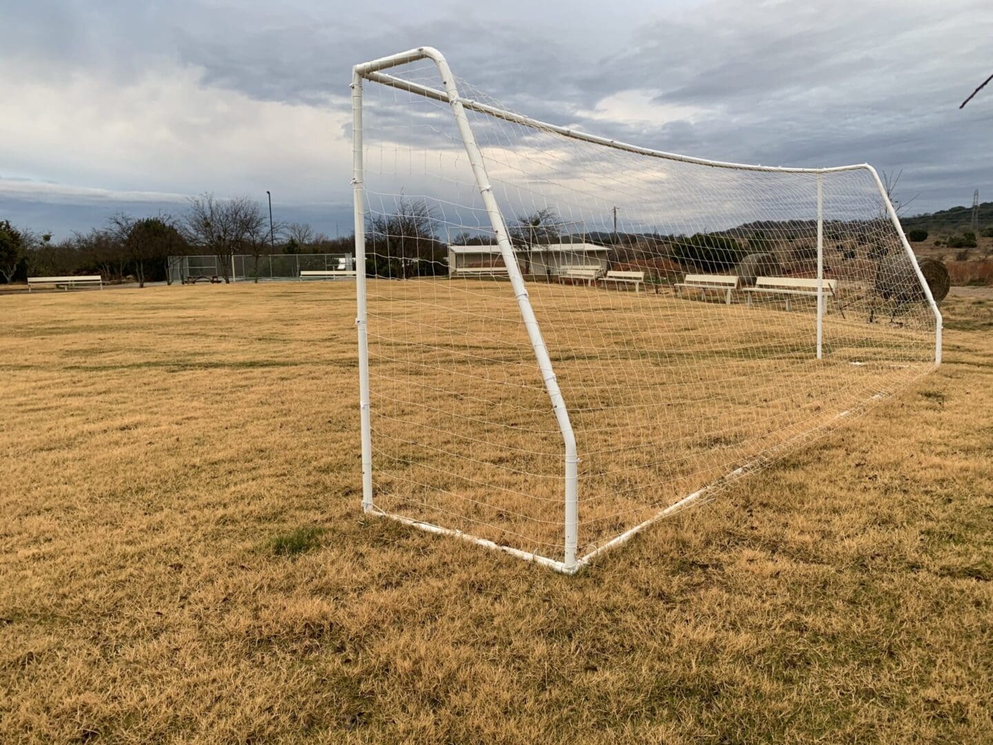 A soccer goal in the middle of an empty field.