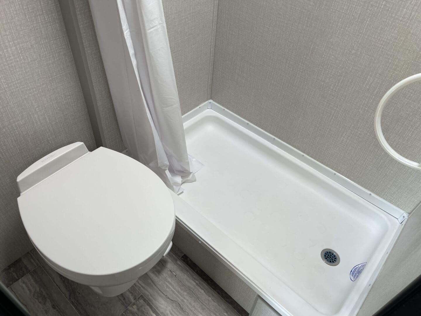 A bathtub and the toilet seat on the wooden flooring