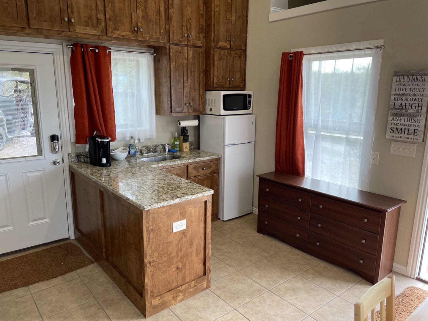 A kitchen with a refrigerator, microwave and sink.