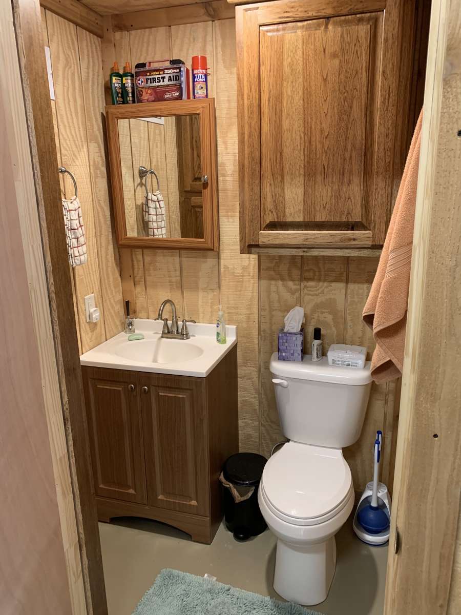 A small wooden bathroom with faucet and toilet