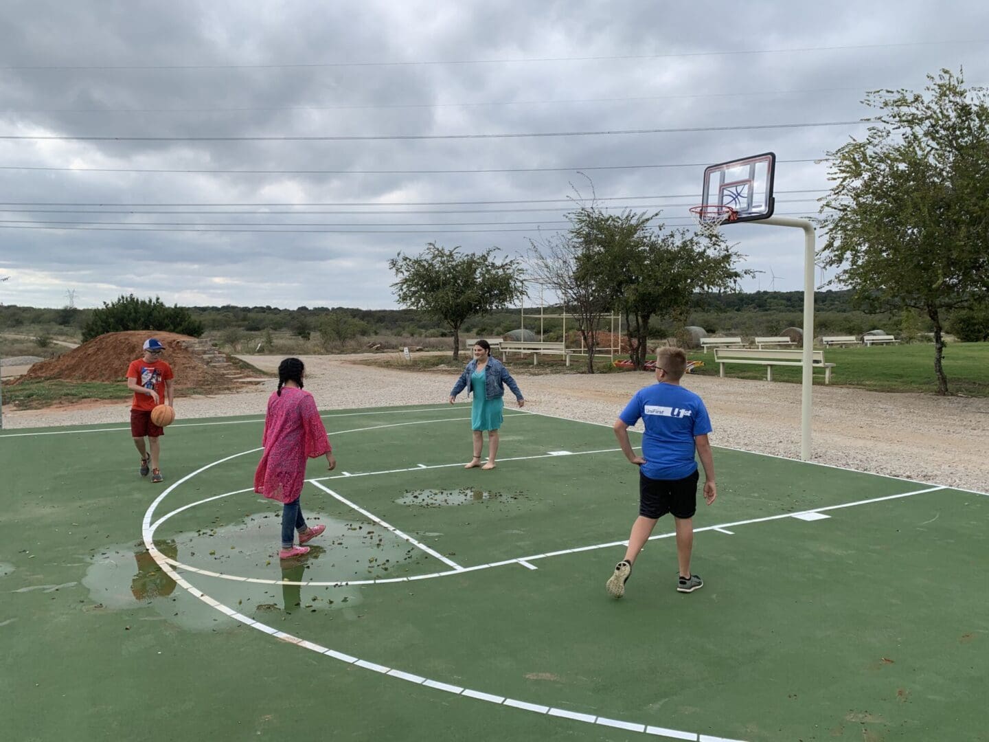 A group of people playing basketball on an outdoor court.