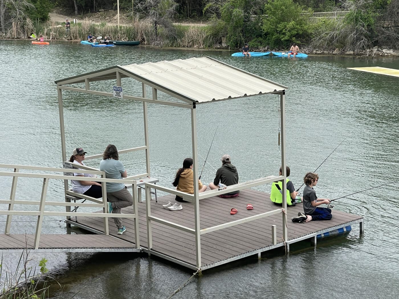 A group of people sitting on a dock on a lake.