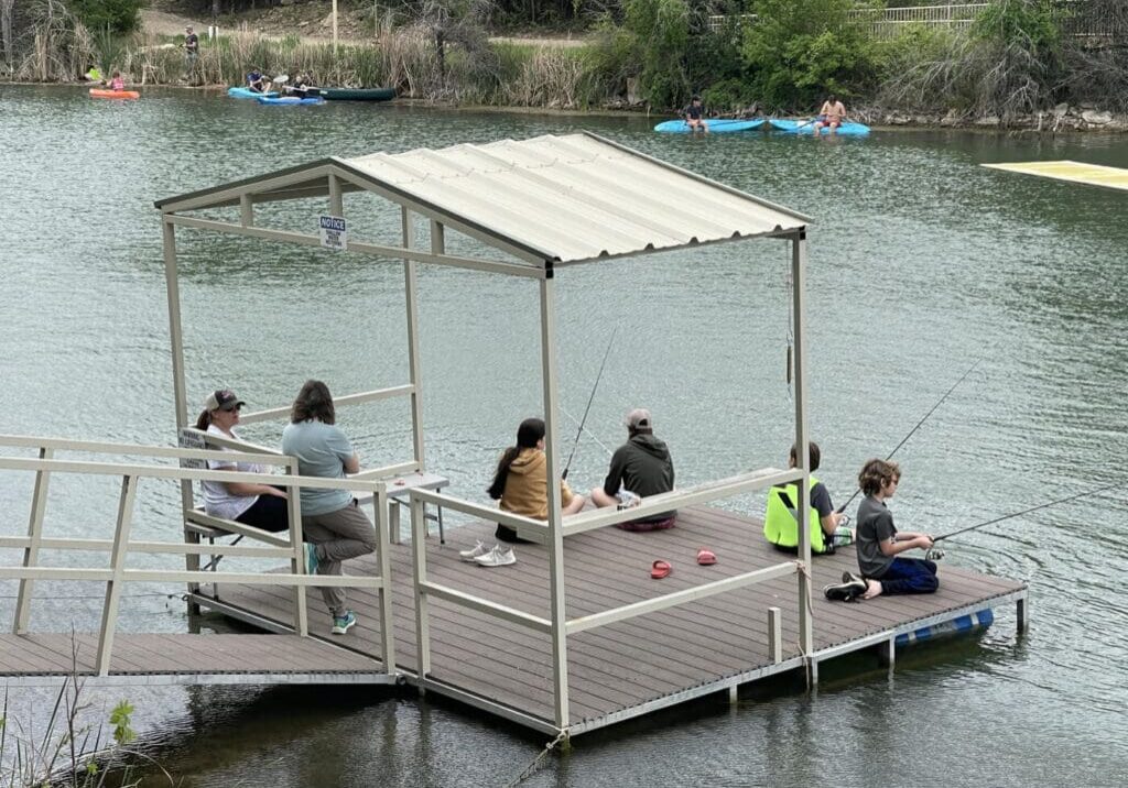 A group of people sitting on a dock on a lake.